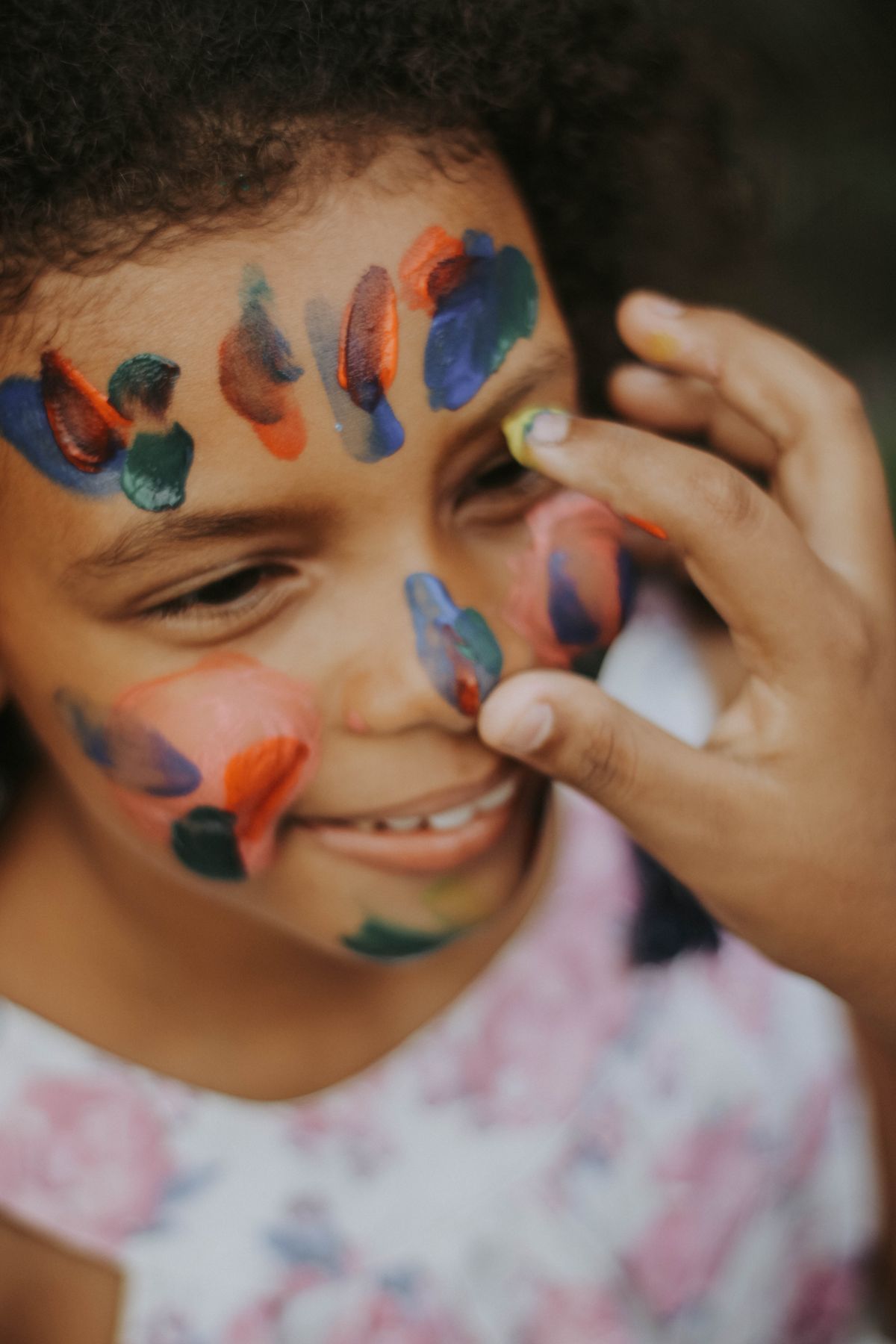 A smiling child having colorful face paint applied